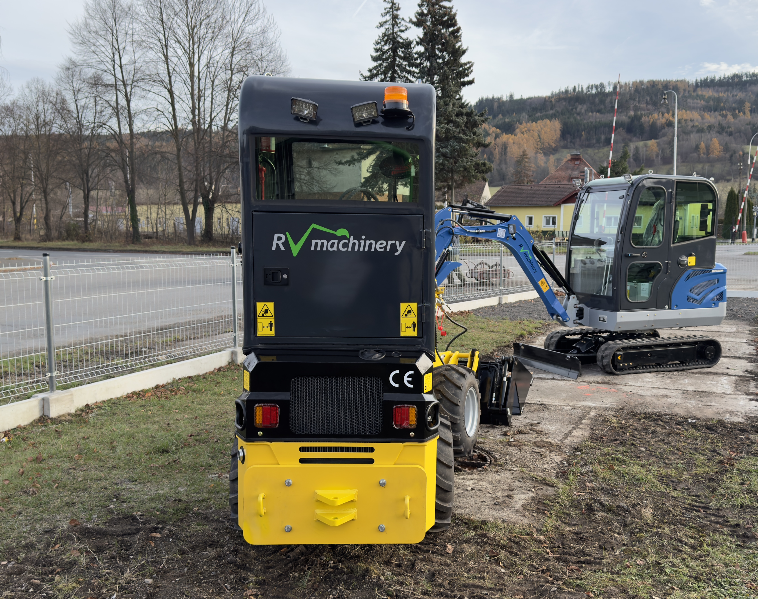 Pohled na zadní část kloubového teleskopického mininakladače R906TS s přístupem k motoru a osvětlením pro bezpečné použití v terénu.